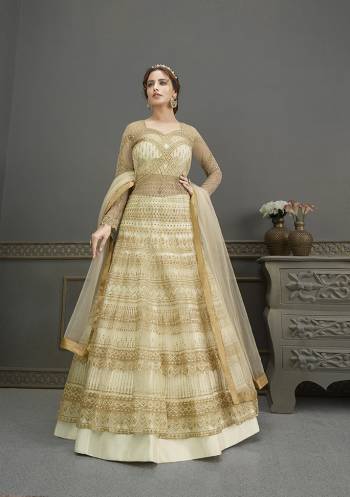 Flaunt Your Rich And Elegant Taste Wearing This Designer Semi-Stitched Floor Length Gown In Beige Color Paired With Beige Colored Dupatta. This Pretty Gown And Dupatta Are Fabricated On Net Beautified With Pretty Embroidery And Hand Work Giving An Attractive Look. 