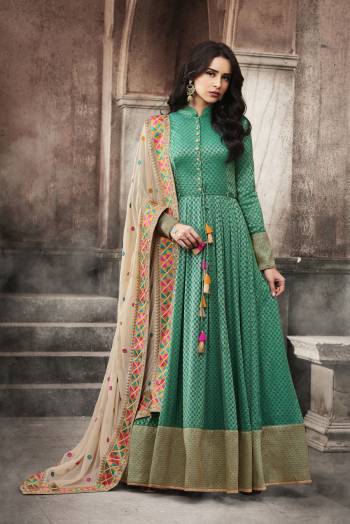 For A Rich And Elegant Look, Grab This Designer Floor Length Suit In Sea Green Color Paired With Beige Colored Dupatta. Its Top Is Fabricated On Jacquard Silk Paired With Santoon Bottom And Chiffon Dupatta. This Suit Will Earn You Lots Of Compliments From Onlookers. Buy Now.