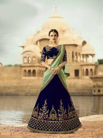 Get Ready For The Upcoming Wedding Season With This Beautiful Lehenga Choli In Blue Color Paired With Contrasting Light Green Colored Dupatta. This Lehenga And Choli Are fabricated On Velvet Paired With Net Fabricated Dupatta. Its Fabrics Are Soft Towards Skin And Easy To Carry All Day Long.