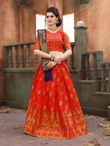 Orange Color Induces Perfect Summery Appeal To Any Outfit, Grab This Lehenga Choli In Orange Color Paired With Contrasting Navy Blue Colored Dupatta. This Lehenga Choli And Dupatta Are Fabricated On Banarasi Art Silk Beautified With Weave All Over. Buy This Lehenga Choli Now.