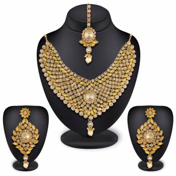 Here Is A Heavy Necklace Set To Pair Up With Your Heavy Ethnic Dress Such As Heavy Lehenga Or Floor Length Suit. This Set Is Also Suitable For Bridal Wear. It Is In Golden Color Beautified With White And Yellow Colored Stones, Buy Now.