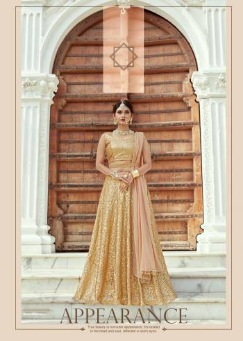 Featuring a beige and gold flared lehenga skirt crafted in net with sequin embellishment. It comes with a matching sleeveless bow style back blouse with sequin embellishment all ove. It comes along with georgette base beige dupatta with hangs on both the sides. 
