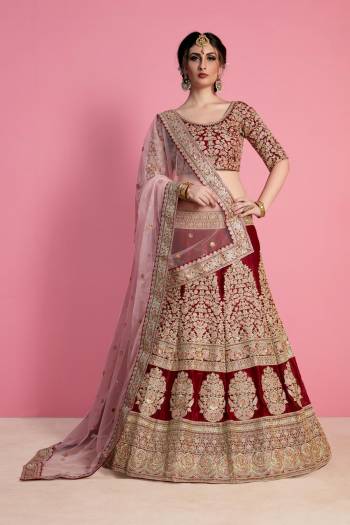 For A Royal Queen Like Look, Grab This Heavy Designer Lehenga Choli In Maroon Color Paired With Light Pink Colored Dupatta. Its Blouse And Lehenga Are Fabricated On Velvet Silk Paired With Net Fabricated Dupatta. Its All Over Heavy Embroidery And Pretty Color Combination Will Earn You Lots Of Compliments From Onlookers.