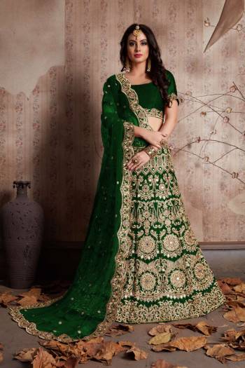 Dark Green color velvet lengha choli with zari embroidery and mirror work all over. It is paired with a Green color net cutwork dupatta with mirror work.