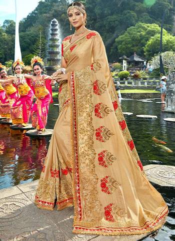 Flaunt your rich and elegant taste wearing this designer saree in beige color paired with beige colored blouse. This saree is fabricated on shimmer fancy fabric paired with art silk fabricated blouse. It has golden and contrasting red colored embroidery over the saree and blouse.