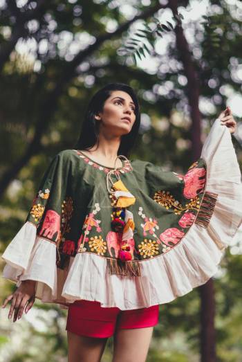 Cute elephant embroidered poncho of Olive green khadi fabric embilished with jute tassel lace and multi pom pom hangings with conical caps. Attached with off white frill all over the poncho