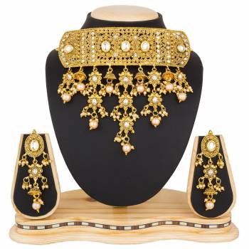 Grab This Beautiful And Attractive Looking Heavy Choker Necklace Set In Golden Color Paired With Heavy Earrings Set. This Set Is Beautified With Stone And Moti Work. It Can Be Paired With Any Colored Traditional Attire. Buy Now.