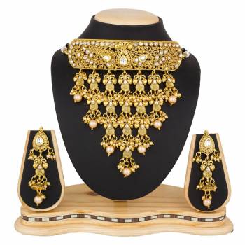 Grab This Beautiful And Attractive Looking Heavy Choker Necklace Set In Golden Color Paired With Heavy Earrings Set. This Set Is Beautified With Stone And Moti Work. It Can Be Paired With Any Colored Traditional Attire. Buy Now.