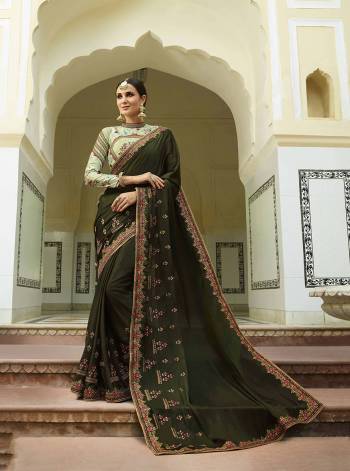 Get Ready For The Upcoming Wedding Season With This Designer Saree In Dark Olive Green Color Paired With Pastel Green Colored Blouse. This Saree And Blouse Are Silk based With A Touch Of Tissue In Blouse. Carry Minimal Accessories With This Pretty Heavy Saree. 