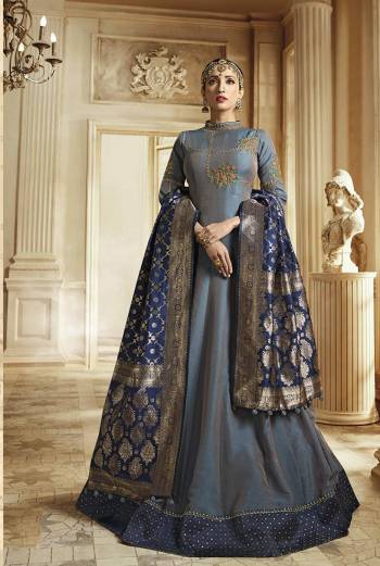 Rich And Elegant Looking Designer Floor Length Suit Is Here In Grey Color Paired With Contrasting Navy Blue Colored Dupatta. Its Top IS Soft Silk Based Paired With Santoon Bottom And Banarasi Art Silk Fabricated Dupatta. It Has Very Rich Color Pallete Which Will Earn You Lots Of Compliments From Onlookers. 