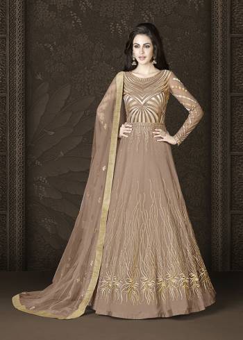 Grab This Amazing Designer Floor Length Suit In A Very Trendy Shade In Light Brown Color. Its Heavy Embroidered Top Is Fabricated On Net Paired With Art Silk Bottom and Net Dupatta. This Suit Ensures Superb Comfort All Day Long. 