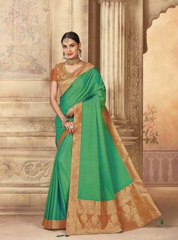 Celebrate This Festive Season Wearing This Designer Saree In Green Color Paired With Contrasting Orange Colored Blouse. This Saree And Blouse Are Silk Based Beautified With Embroidery And Prints. 