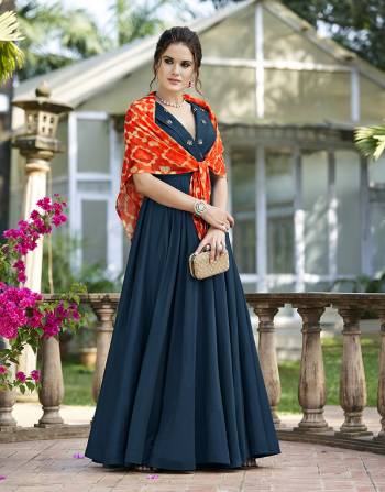 You Will Definitely eArn Lots Of Compliments Wearing This Designer Gown In Blue Color Paired With An Orange Colored Printed Stole. This Pretty gown Is Beautified With Hand Work Butti. 