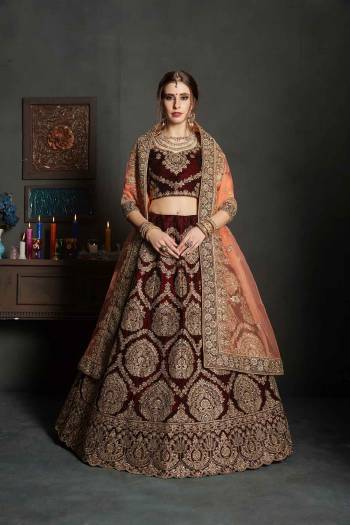 Here Is A Perfect Bridal Look For You In The Running Treand With This Heavy designer Lehenga Choli In Maroon Color Paired With Contrasting Peach Colored Dupatta. This Lehenga Choli Is Velvet Based Paired With Net Fabricated Dupatta.Its Fabric Also Ensures Superb Comfort Throughout The Gala