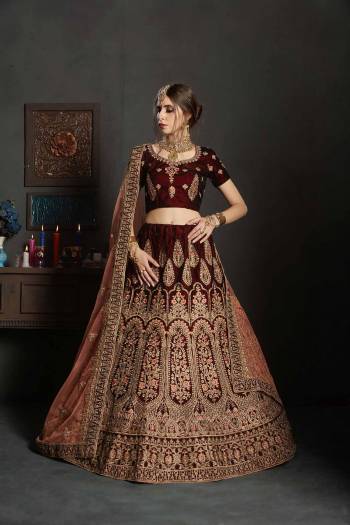 Get Ready For Your Big Day With This Latest Bridal Trend, Wearing This Heavy Designer Lehenga Choli In Maroon Color Paired With Contrasting Peach Colored Dupatta. This Heavy Embroidered Lehenga Choli Is Fabricated On Velvet Paired With Net Fabricated Dupatta. It Is Beautified With Heavy Embroidery and Stone Work. Buy Now