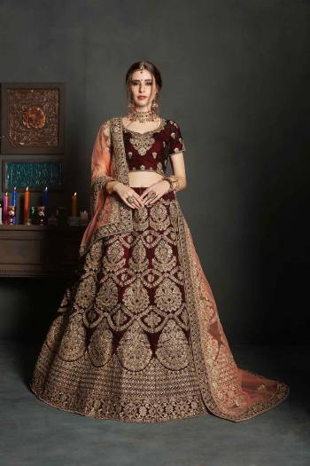 Here Is A Perfect Bridal Look For You In The Running Treand With This Heavy designer Lehenga Choli In Maroon Color Paired With Contrasting Peach Colored Dupatta. This Lehenga Choli Is Velvet Based Paired With Net Fabricated Dupatta.Its Fabric Also Ensures Superb Comfort Throughout The Gala