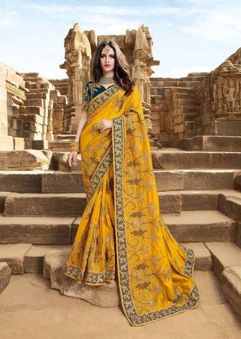 Catch All The Limelight At The Next Wedding You Attend Wearing This Heavy Designer Saree In Yellow Color Paired With Contrasting Prussian Blue Colored Blouse. This Saree Is Fabricated On Satin Silk Paired With Art Silk Fabricated Blouse. 