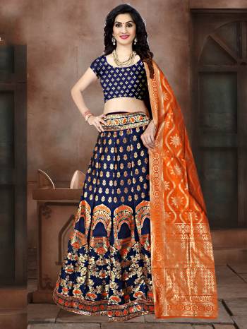 Shine Bright In This Very Beautiful Designer Lehenga Choli In Navy Blue Color Paired With Contrasting Orange Colored Dupatta. This Lehenga Choli Is Fabricated On Banarasi Jacquard Silk Beautified With Weave All Over. 