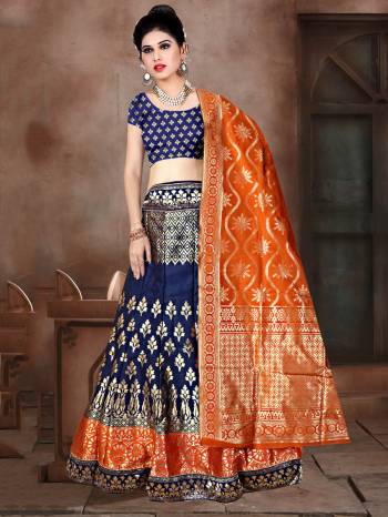 Shine Bright In This Very Beautiful Designer Lehenga Choli In Navy Blue Color Paired With Contrasting Orange Colored Dupatta. This Lehenga Choli Is Fabricated On Banarasi Jacquard Silk Beautified With Weave All Over. 