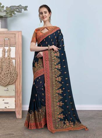 Look The Most Attractive Of All Wearing This Heavy Designer Saree In Navy Blue Color Paired With Contrasting Orange Colored Blouse. This Saree And Blouse Are Silk Based Beautified With Heavy Detailed Embroidery Which Will Earn You Lots Of Compliments From Onlookers. 