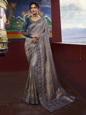 Flaunt Your Rich And Elegant Taste Wearing This Heavy Designer Saree In Grey Color Paired With Contrasting Navy Blue Colored Blouse. This Saree And Blouse are Silk based Beautified With Weave And Embroidery All Over. 