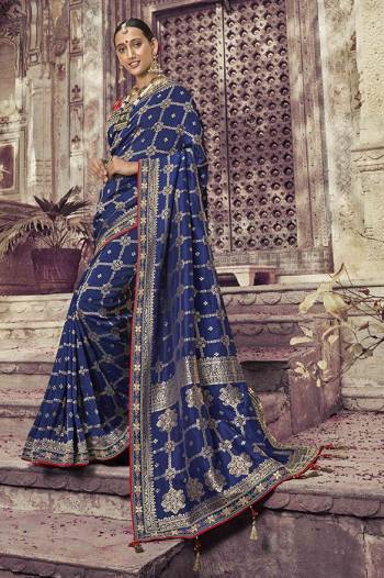 You Will Definitely Earn Lots Of Compliments Wearing This Designer Saree In Navy Blue Color Paired With Contrasting Red Colored Blouse. This Saree And Blouse Are Rich Silk Based Beautified With Weave And Attractive Embroidery. 