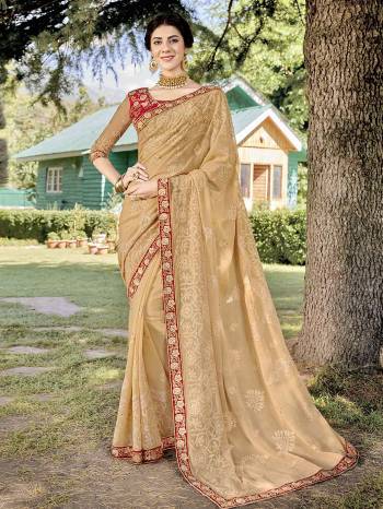 Here Is A Lovely Designer Saree In Light Beight Color Paired With Contrasting Red Colored Blouse. This Pretty Tone To Tone Embroidered Saree Is Fabricated On Georgette Paired With Art Silk Fabricated Blouse.