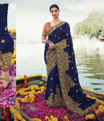 Attract All Wearing This Heavy Designer Saree In Royal Blue Color Paired With Contrasting Dark Peach Colored Blouse. This Saree And Blouse Are Silk Based Beautified With Heavy Embroidery All Over. 