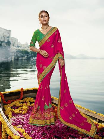 Get Ready For The Upcoming Wedding And Festive Season With This Heavy Designer Saree In Rani Pink Color Paired With Contrasting Green Colored Blouse. This Saree And Blouse Are Silk Based, Its Rich Color  Pallete Will Earn You Lots Of Compliments From Onlookers. 