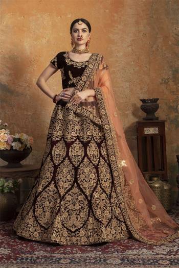 Here Is A Perfect Bridal Look For You In The Running Treand With This Heavy designer Lehenga Choli In Dark Maroon Color Paired With Contrasting Peach Colored Dupatta. This Lehenga Choli Is Velvet Based Paired With Net Fabricated Dupatta.Its Fabric Also Ensures Superb Comfort Throughout The Gala.