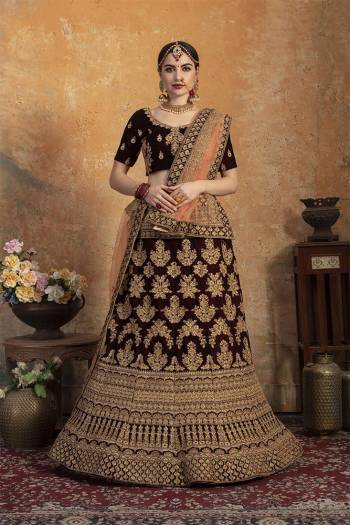 Get Ready For Your Big Day With This Latest Bridal Trend, Wearing This Heavy Designer Lehenga Choli In Dark Maroon Color Paired With Contrasting Peach Colored Dupatta. This Heavy Embroidered Lehenga Choli Is Fabricated On Velvet Paired With Net Fabricated Dupatta. It Is Beautified With Heavy Embroidery. Buy Now