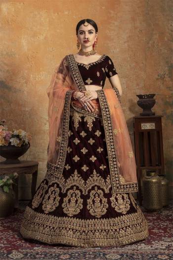 Get Ready For Your Big Day With This Latest Bridal Trend, Wearing This Heavy Designer Lehenga Choli In Dark Maroon Color Paired With Contrasting Peach Colored Dupatta. This Heavy Embroidered Lehenga Choli Is Fabricated On Velvet Paired With Net Fabricated Dupatta. It Is Beautified With Heavy Embroidery. Buy Now