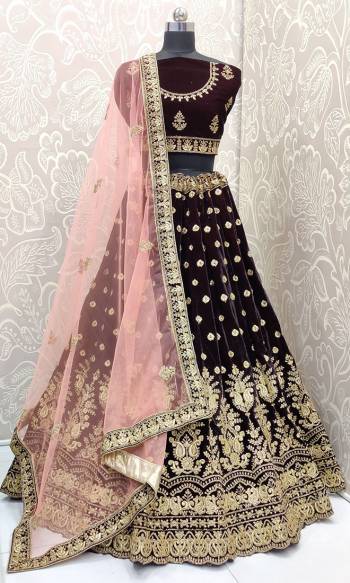 Get Ready For The Upcoming Wedding Season With This Heavy Designer Lehnega Choli In Wine Color Paired With Baby Pink Colored Dupatta. Its Blouse And Lehenga Are Fabricated on Velvet Paired With Net Fabricated Dupatta. It Has Lovely Heavy Detailed Embroidery Giving You An Attractive Look. 