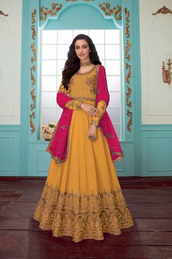 Get Ready For The Upcoming Wedding Season With This Designer Floor Length Suit In Yellow Color Paired With Rani Pink Colored Dupatta. Its Embroidered Top And Dupatta Are Georgette Based Paired With Santoon Fabricated Bottom. Buy Now.