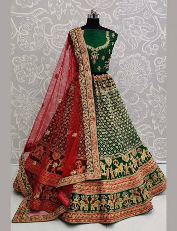 Here Is A Heavy Designer Lehenga Choli In A Proper Traditional Look With Traditional Color Combination In Dark Green Colored Blouse Paired With Dark Green Colored Heavy Embroidered Lehenga And Contrasting Red Colored Dupatta. This Pretty Blouse And Lehenga Are Satin Based Paired With Net Fabricated Dupatta. 