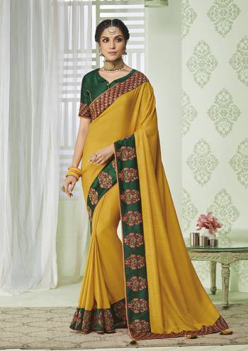 Enhance Your Personality Wearing This Rich Silk Based Designer Saree In Yellow color Paired With Contrasting Dark Green Colored Blouse. It Is Beautified With Pretty Embroidery Over The Lace Border. 