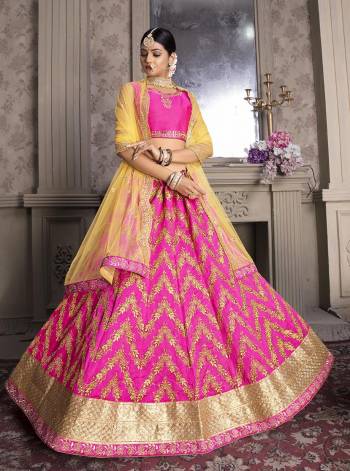 Shine Bright Wearing This Designer Lehenga Choli In Rani Pink Color Paired With Contrasting Yellow Colored Dupatta. Its Blouse And Lehenga Are Fabricated On Art Silk Paired With Net Fabricated Dupatta. 