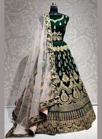 Get Ready For The Upcoming Wedding Season With This Heavy Designer Lehenga Choli In Dark Green Color Paired With Off-White Colored dupatta. This Lehenga Choli Is Fabricated On Velvet Paired With Net Fabricated Dupatta. 