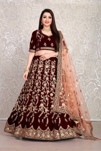 Here Is An Attractive Looking Heavy Designer Lehenga Choli In Maroon Color Paired With Peach Colored Dupatta. This Lehenga Choli Is Velvet Based Paired With Net Fabricated Dupatta. Buy Now.